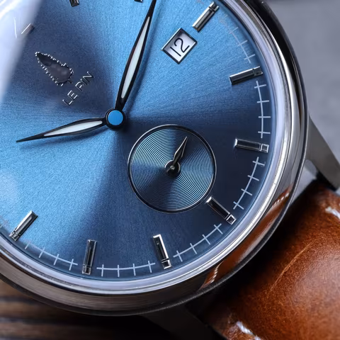 Macro view of the Le Pin blue sunburst dial, showing the applied indices, date window and small seconds sub-dial.